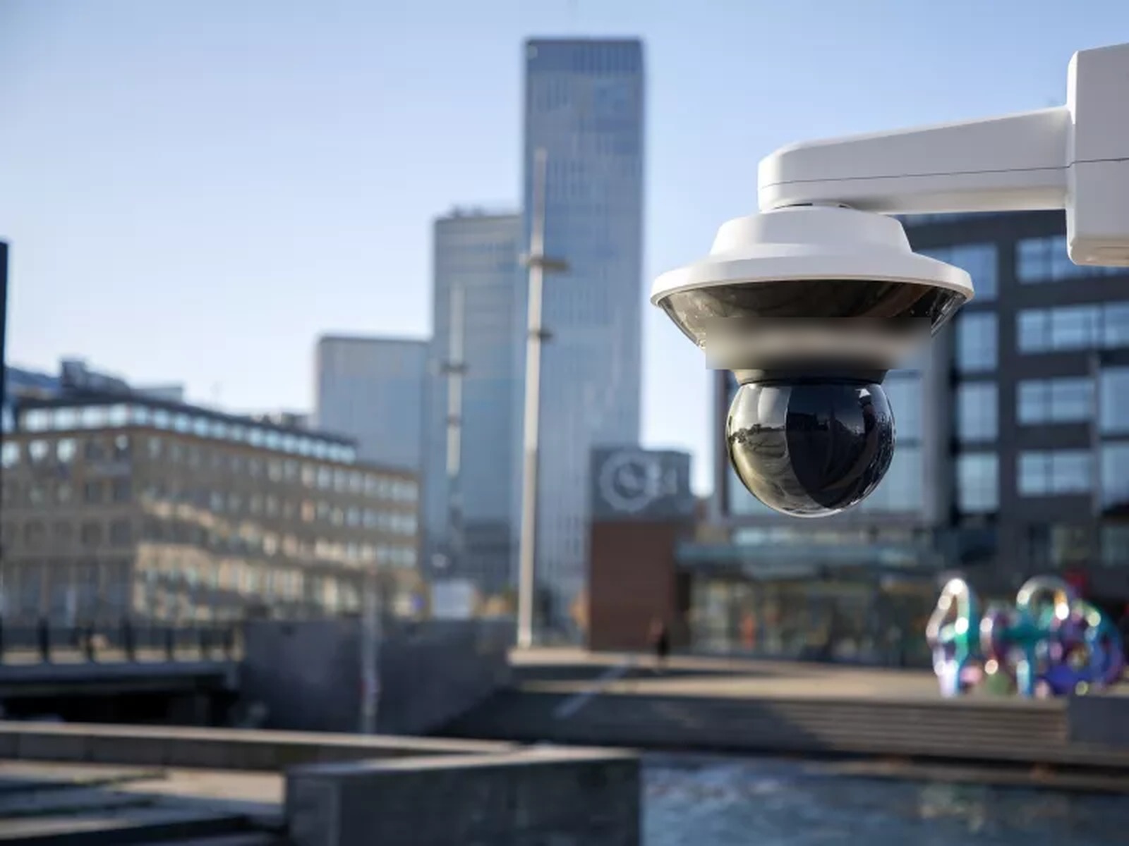 Dome security camera mounted above a city business district on a clear day